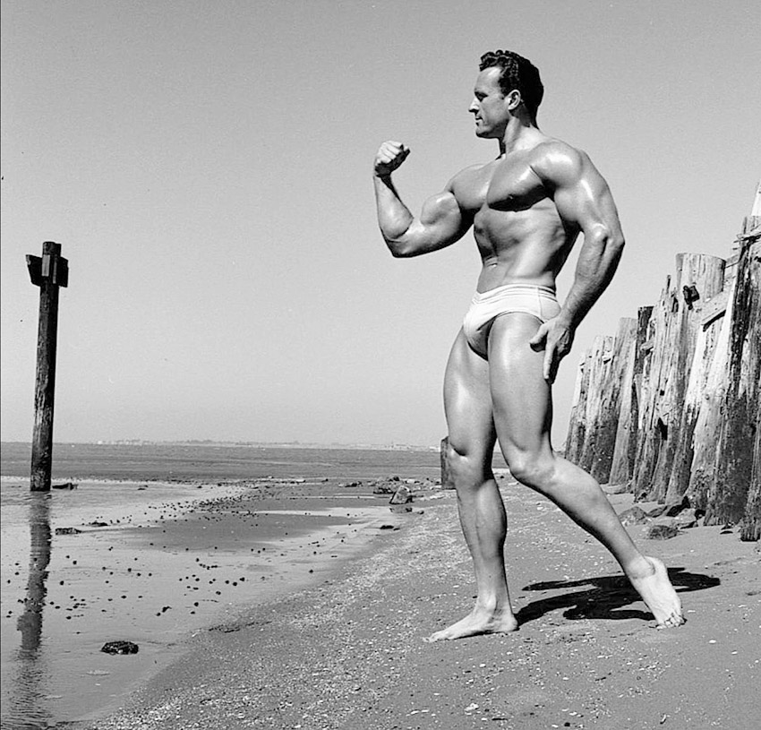 Clarence Ross on the beach posing flexing bicep and forearms 