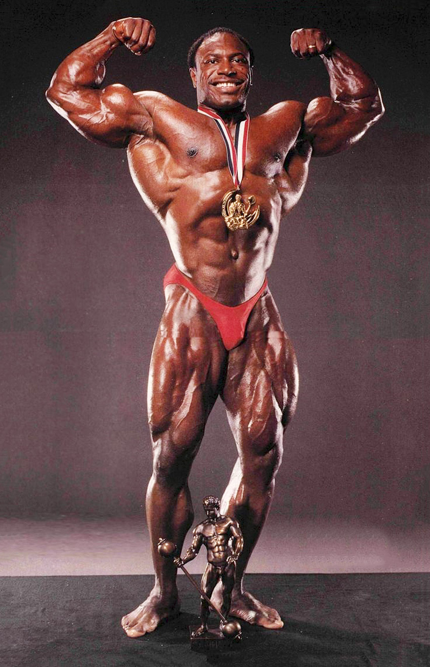 Lee Haney posing his whole body in red shorts