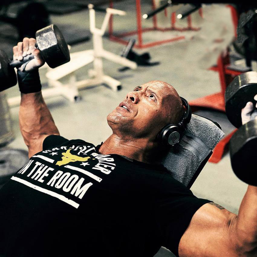 Dwayne Johnson The Rock fully focused on doing incline dumbbell flys in the gym