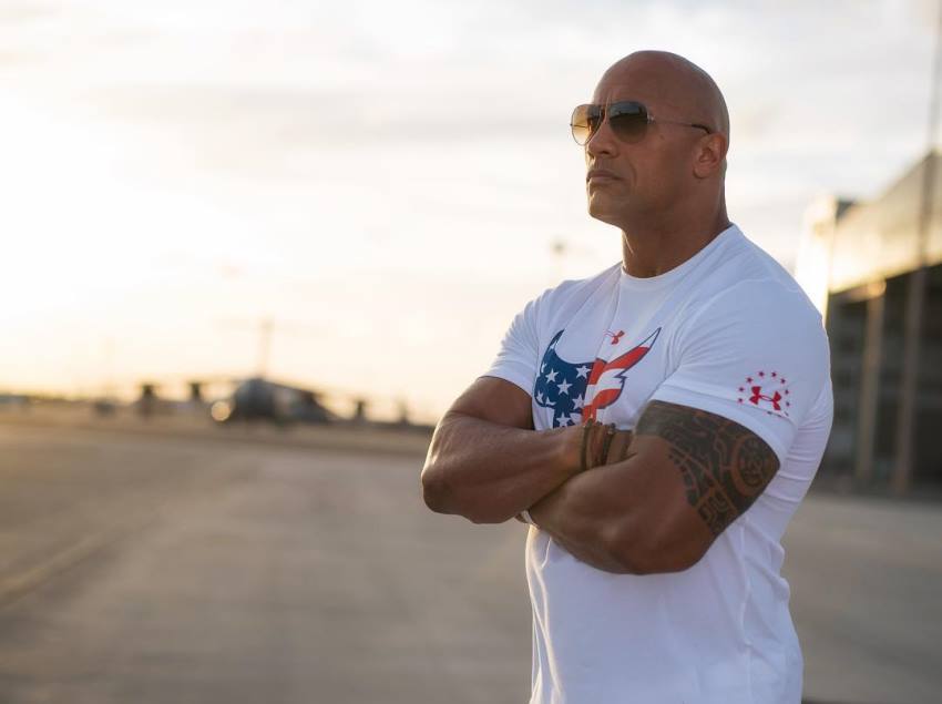 Dwayne Johnson The Rock on the beach with sunglasses with white t-shirt