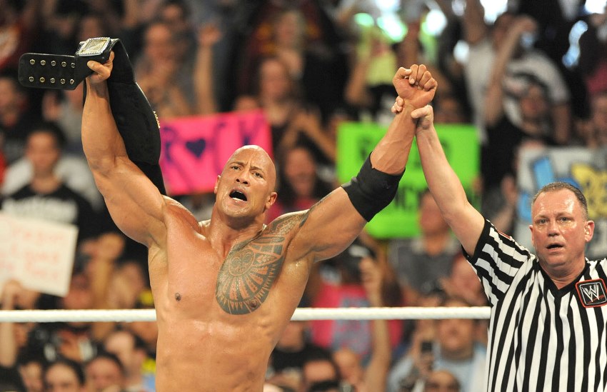 Dwayne Johnson The Rock in the ring with the judge holding his hand and proclaiming him the winner