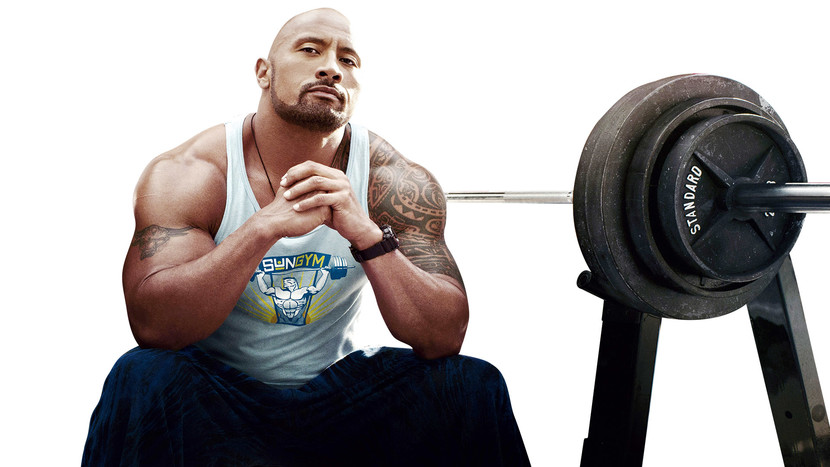 Dwayne Johnson The Rock sitting on a bench with weights