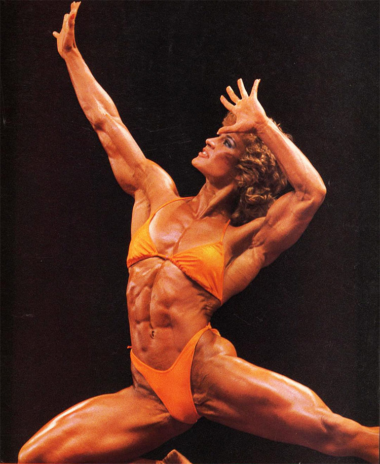 Corinna Everson posing on stage during a routine for a fitness competition.