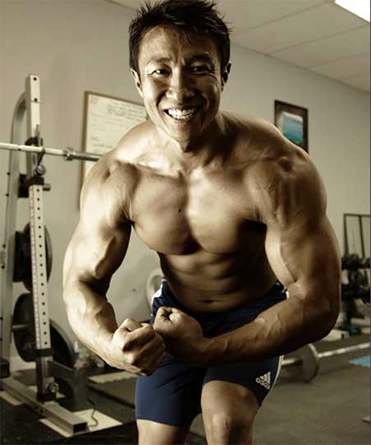 Mike Chang flexing his arms, showing his muscular definition.