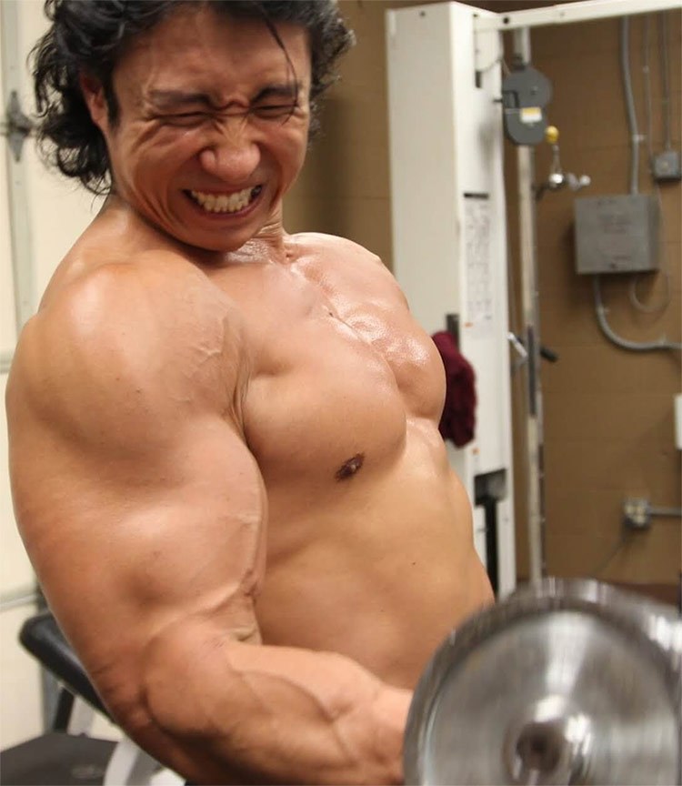 Mike Chang showing everyone the correct form for bicep curls, displaying his huge arms for everyone to see.