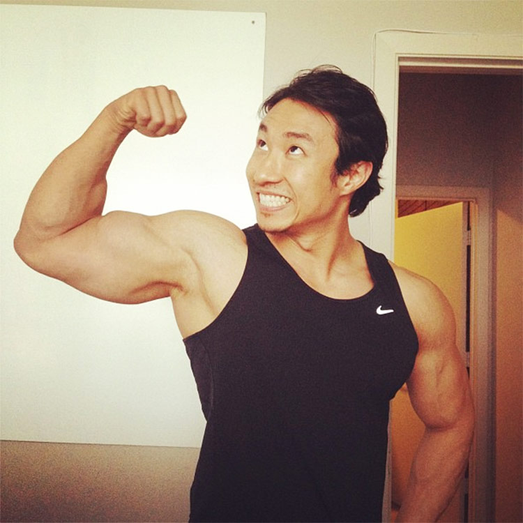 Mike Chang flexing his biceps looking very happy.