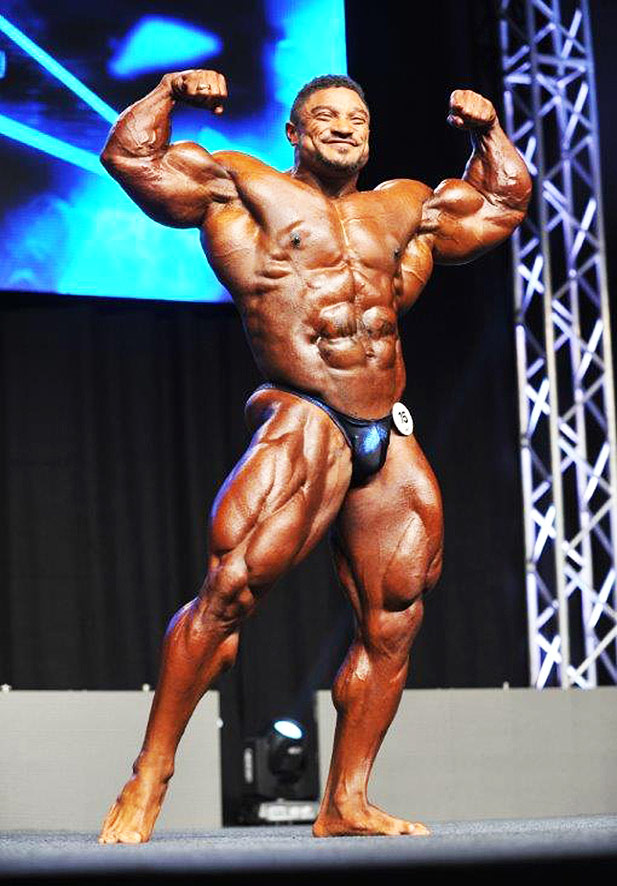 Roelly Winklaar posing on stage during a fitness competition. 