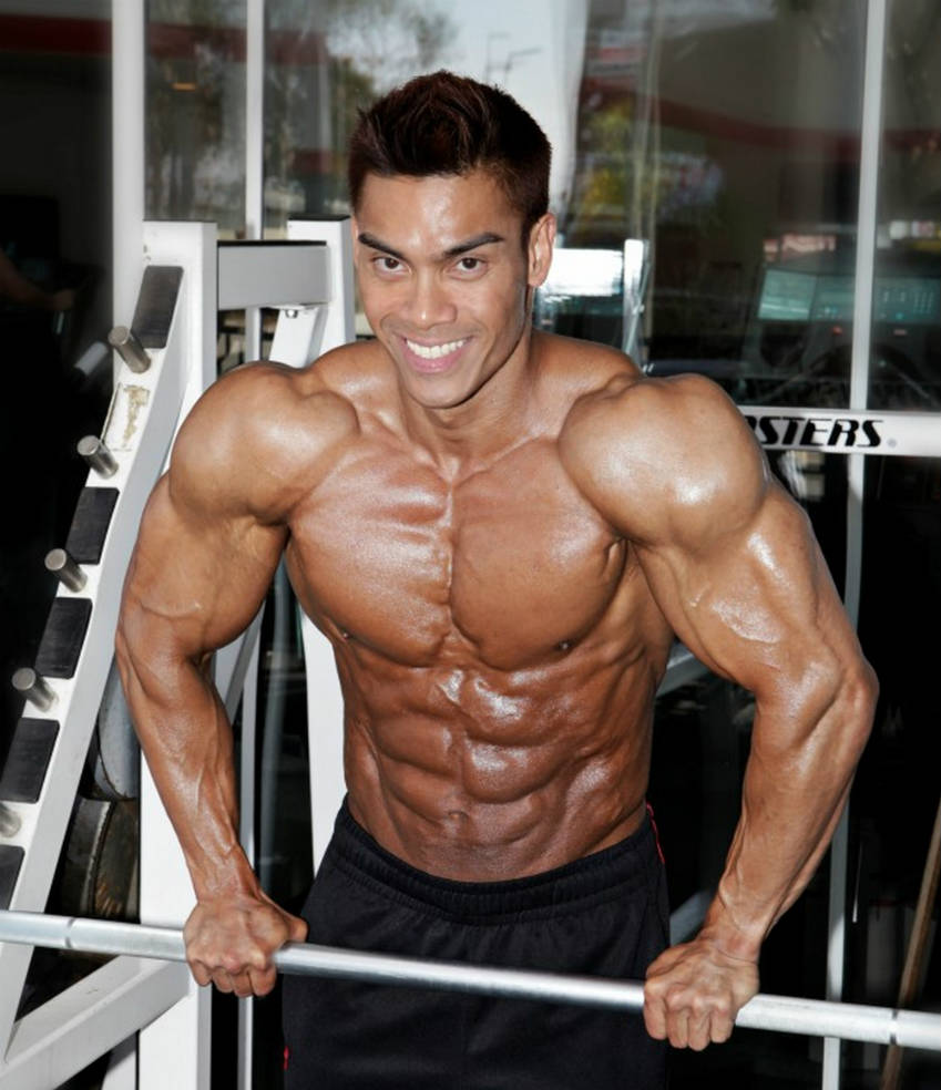Adrian Tan flexing shoulders in the gym