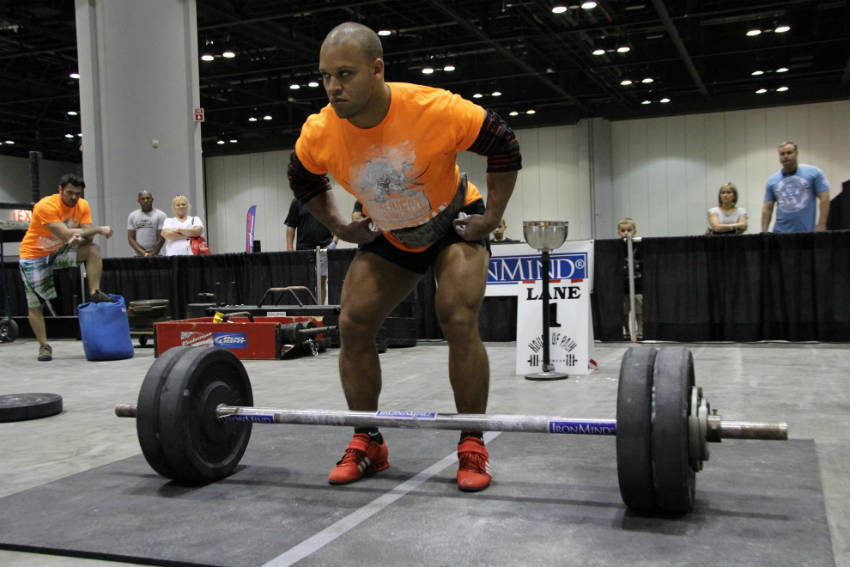 elliott hulse standing over a barbell at a strongman event