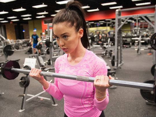 katy hearn completing barbell curl in pink top