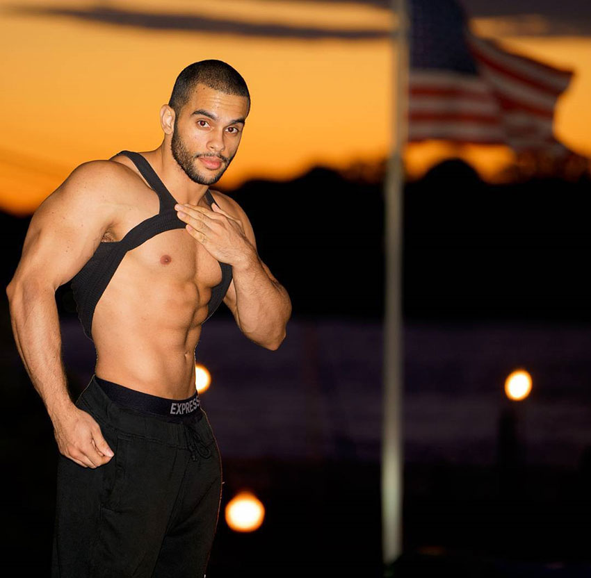 Alex Los Angeles pulling up his t-shirt shwoing his abs with an American flag in the background