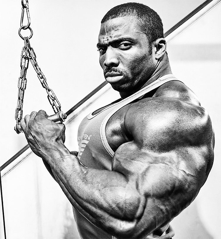 Cedric McMillan tensing his arms for a black and white photoshoot.