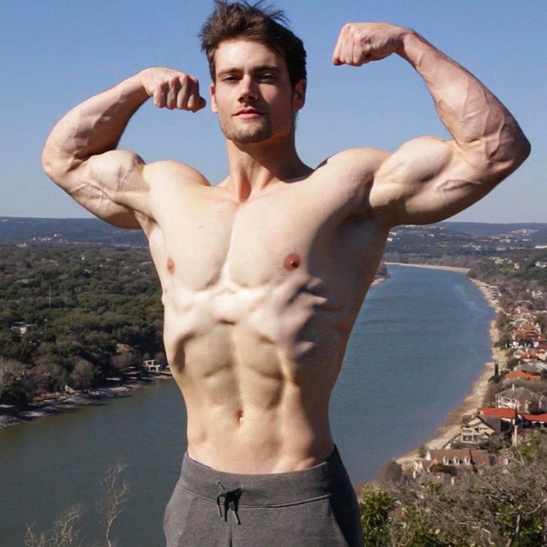 Connor Murphy standing outside with his shirt off flexing his biceps.
