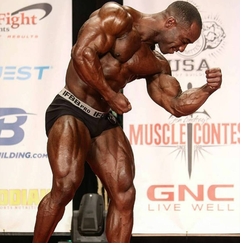 Damion Ricketts tensing his bulging bicep during a competition