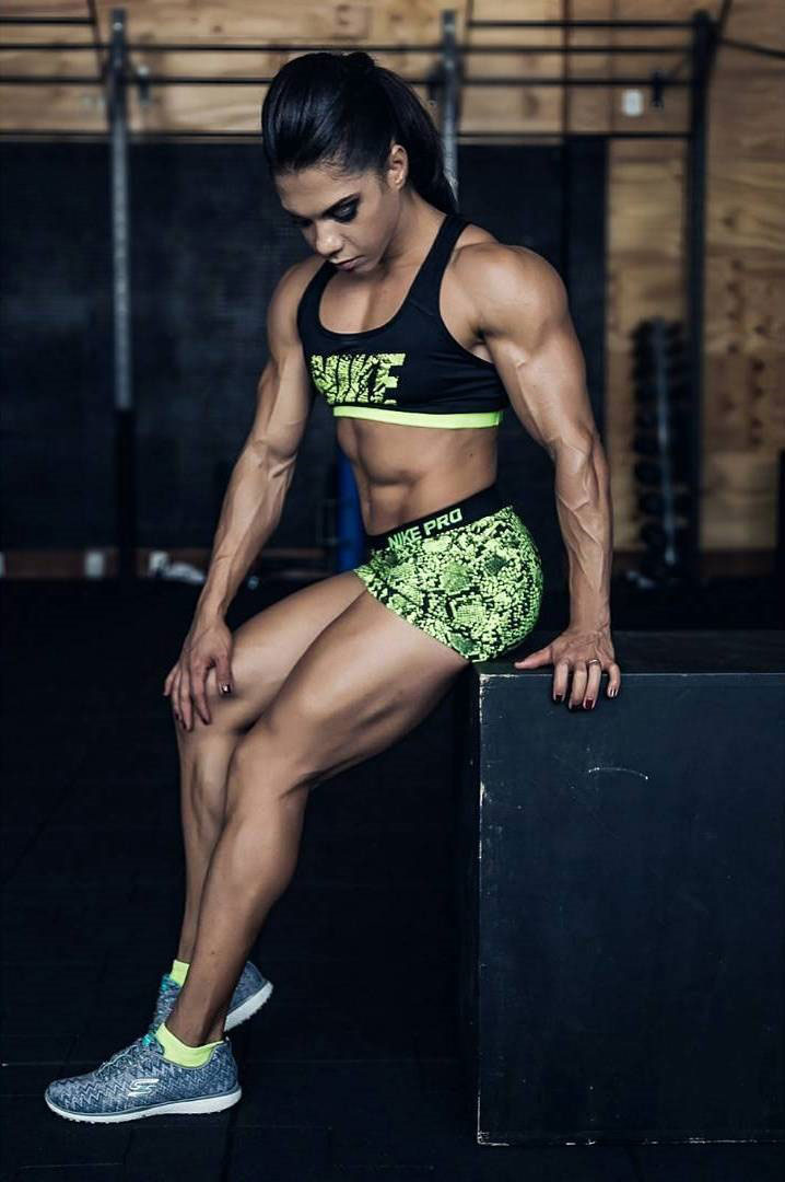 Dani Balbino sitting on a jump box in the gym looking lean and muscular