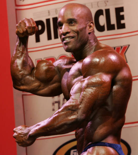 Darrem Charles flexing his bicep at a competition and smiling