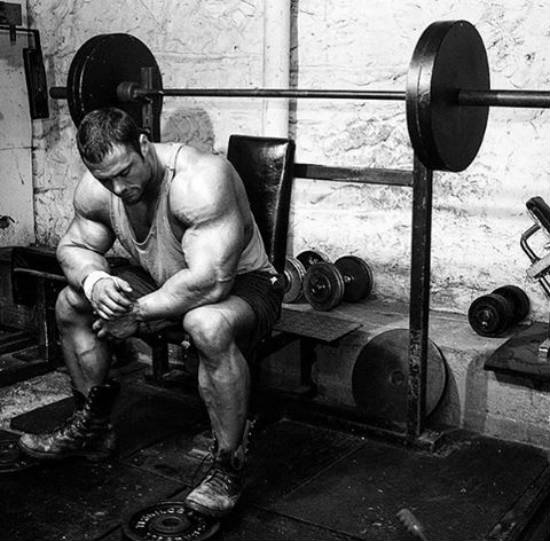 Frank Mcgrath sitting in the gym on a bench in front of the barbell