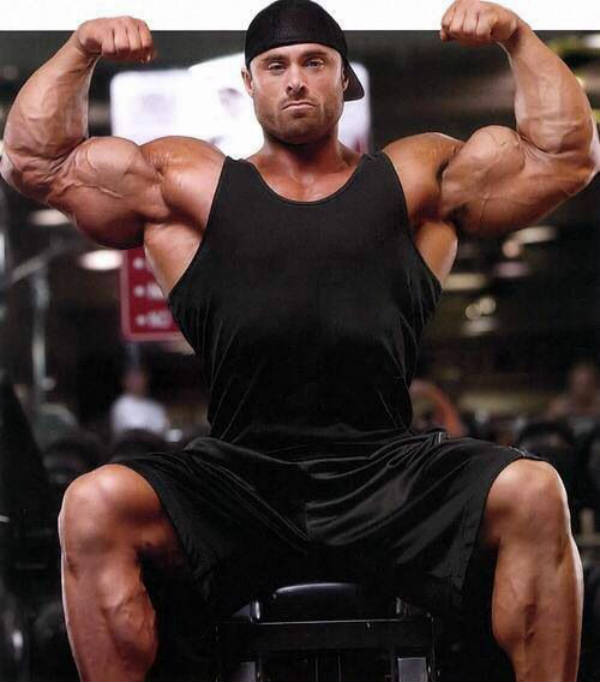 Frank Mcgrath tenses his biceps and looks straight at the camera