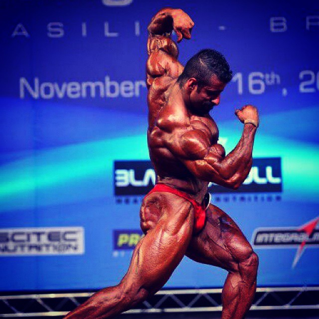 Hadi Choopan posing on the stage, flexing his arms, and impressing the onlookers