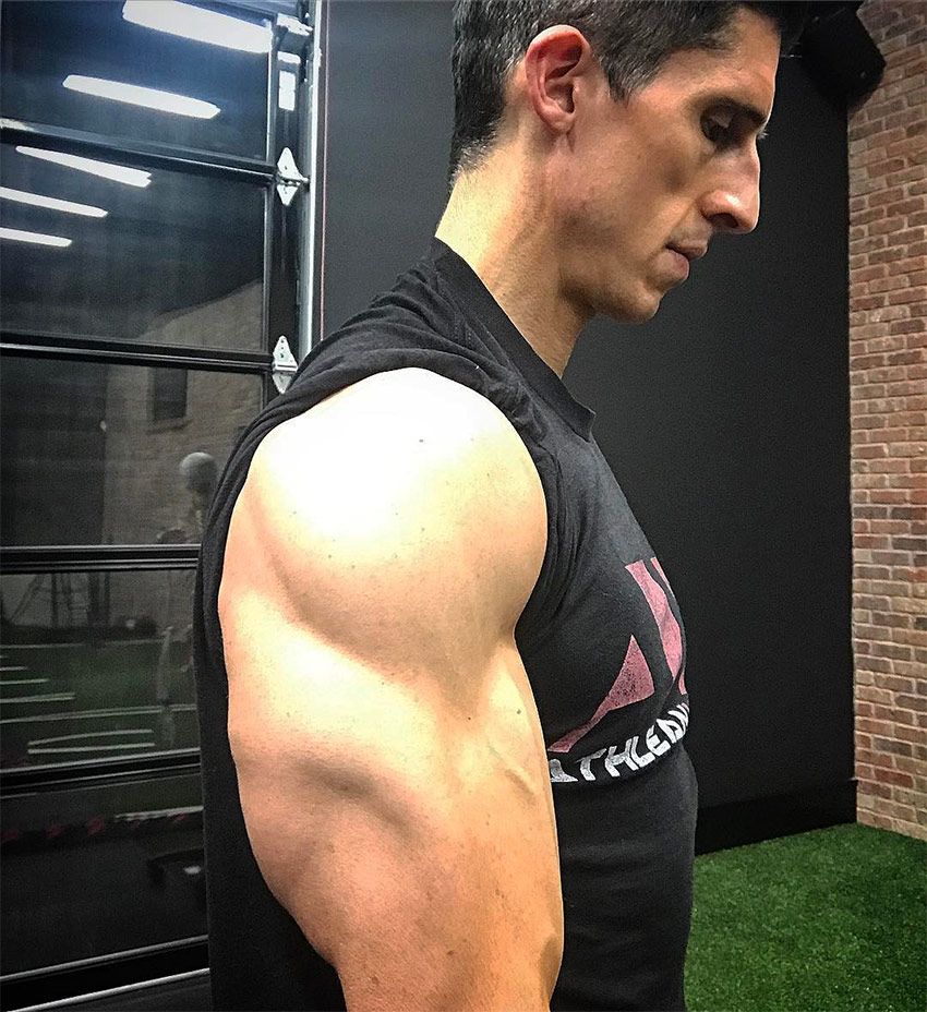 Jeff Cavaliere taking a photo on a side-view so you can see his triceps and size of his biceps, displaying his shredded arms and physique.