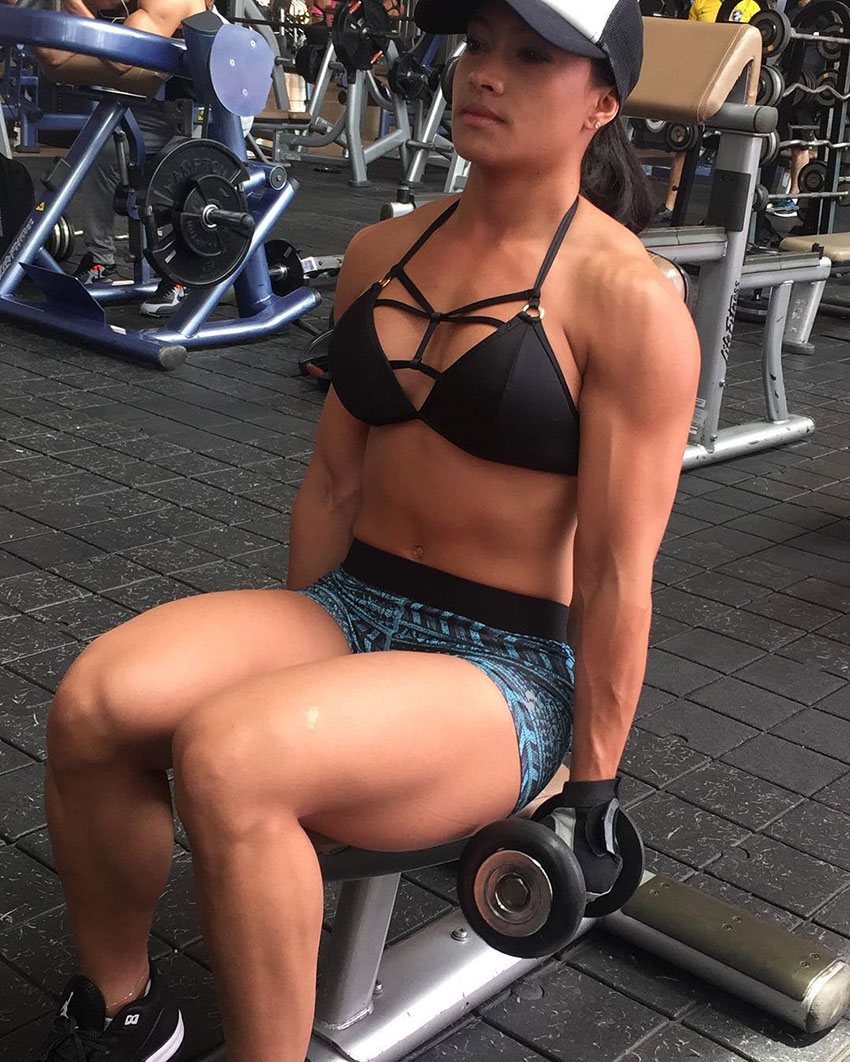 Jessica Olaya in the gym sitting down performing bicep curls 