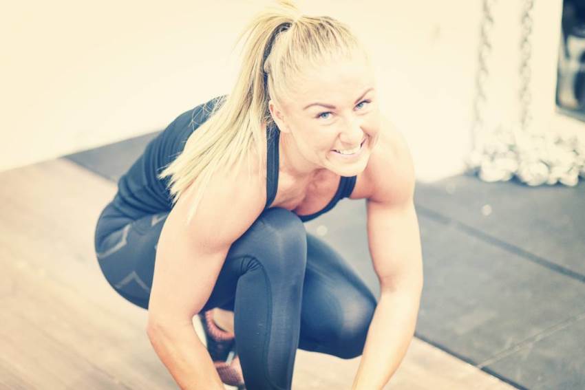 Michaela Augustsson tying her shoelaces while smiling at the camera