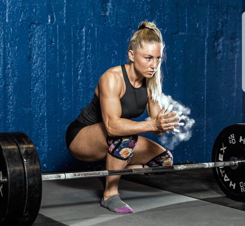 Michaela Augustsson in a squatting position without shoes, preparing to do a deadlift