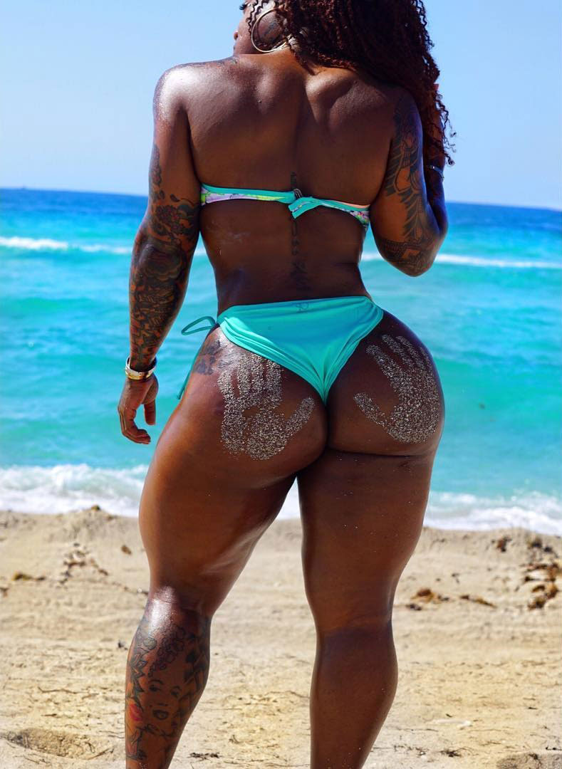 Rahki Giovanni standing on the beach looking into the ocean wearing a blue bikini showing her big glutes and legs 