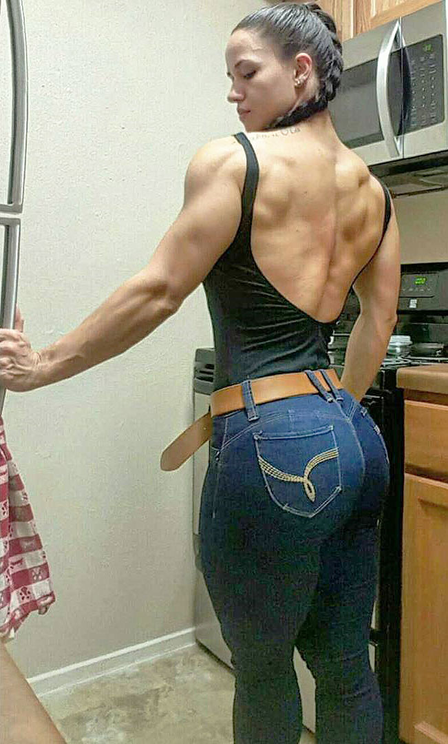 Renee Enos standing in the kitchen flexing her big and strong back wearing a backless t-shirt 