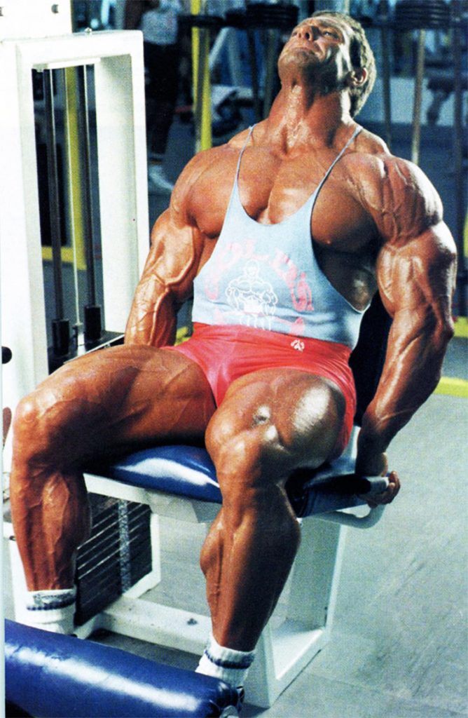 Scott Wilson Bodybuilder Stats, showing his muscular definition in his legs and upper body, while training on a leg press machine.