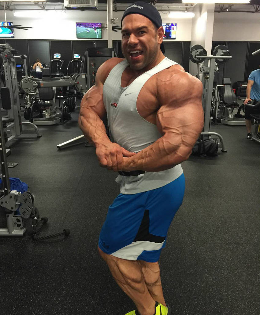 Steve Kuclo standing in the gym tensing his bicep