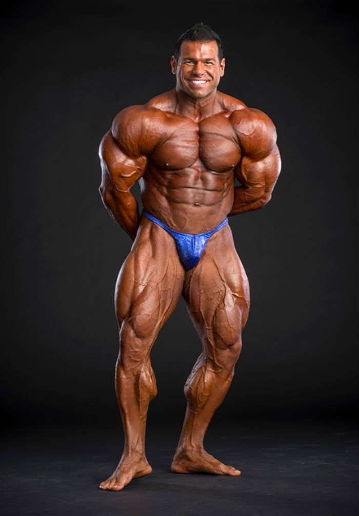 Steve Kuclo posing in full tan and blue trunks 