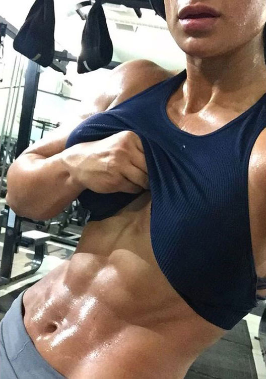 Valia Ayyar lifting up her shirt flexing her abs