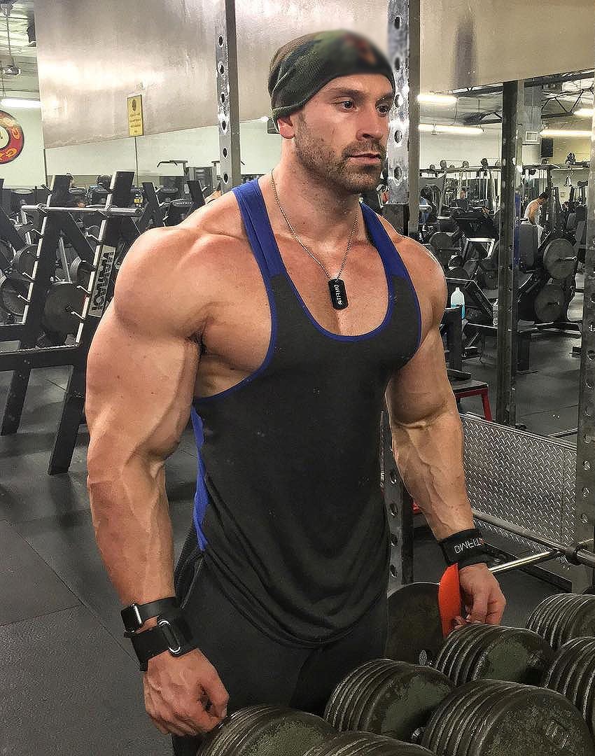 Bradley Martyn profile picture in which he's besides a dumbbell rack, while looking at himself in the mirror