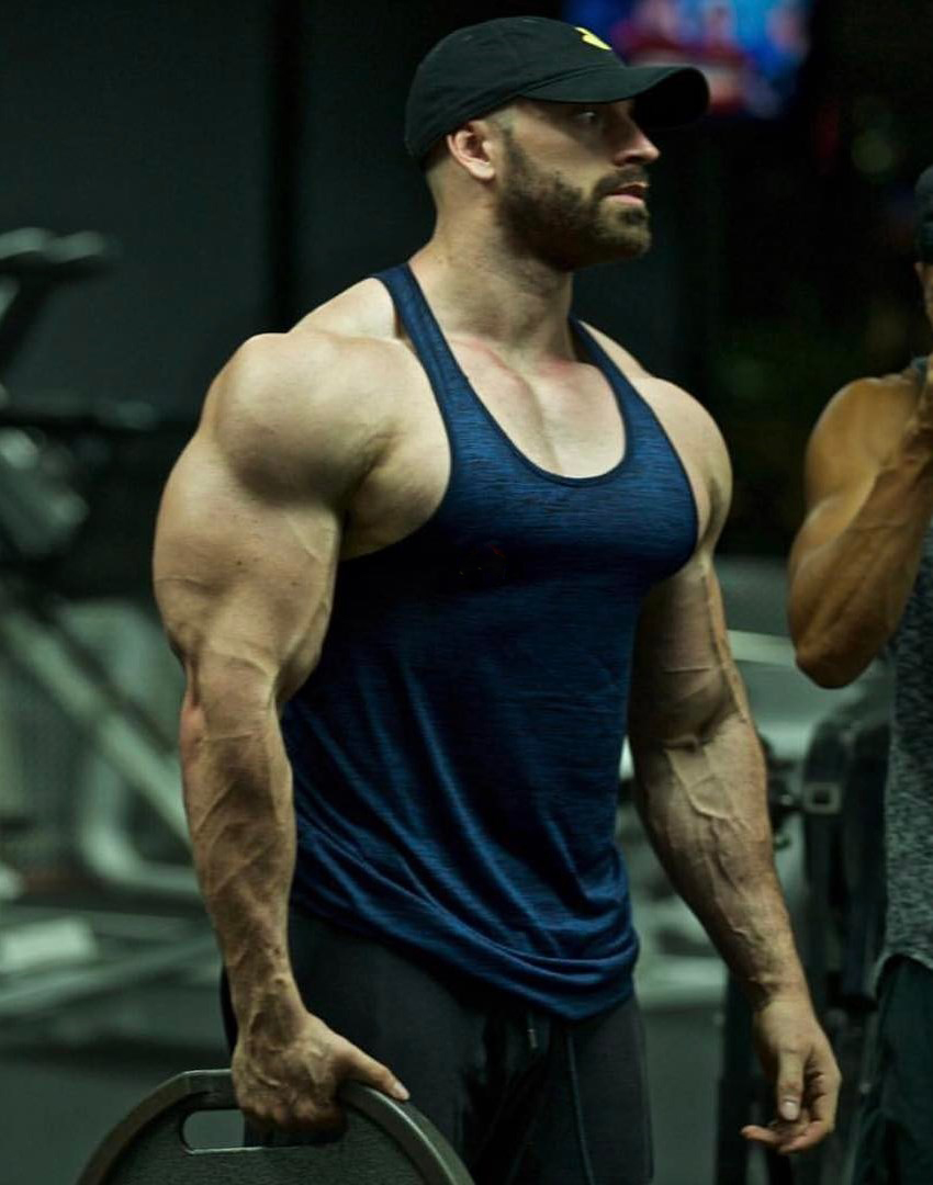 Bradley Martyn sosteniendo un plato de pesas con uno de sus súper vasculares y musculosos brazos