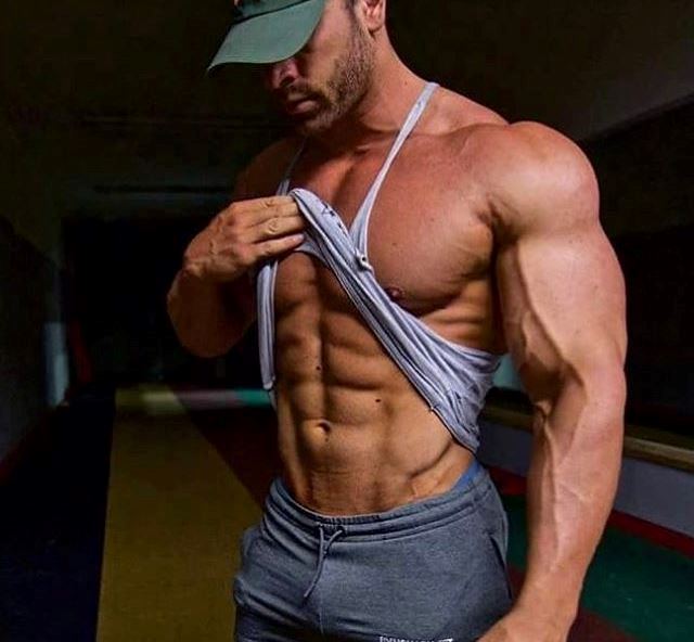 Bradley Martyn lifting his tank top to show his ripped abs