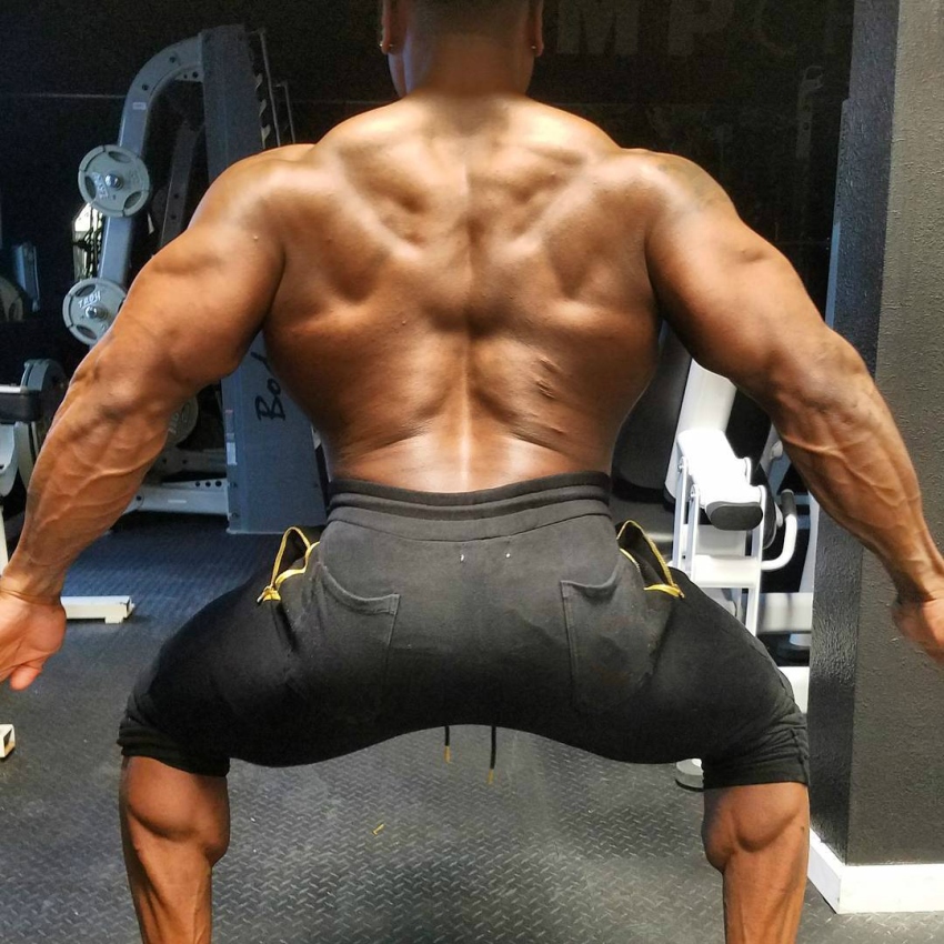 Chris Jones with his back and arms wide spread, showing his muscular lats, traps, and calves