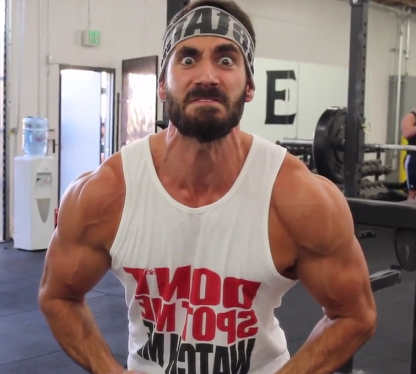 Dom Mazzetti profile picture where he flexes in front of the camera, with an angry and humorous grimace
