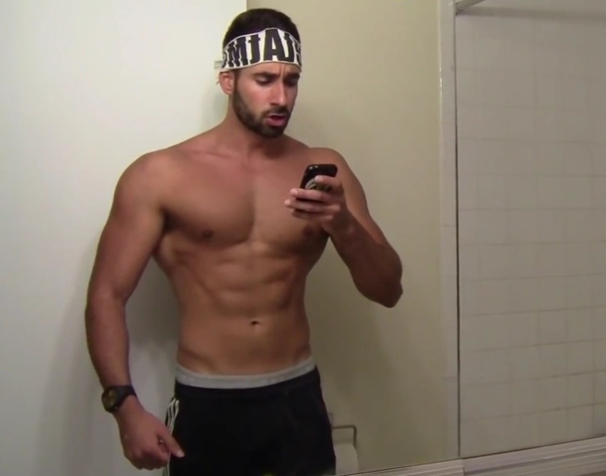 Dom Mazzetti taking a picture of himself in the mirror, showing his abs, chest, and arms