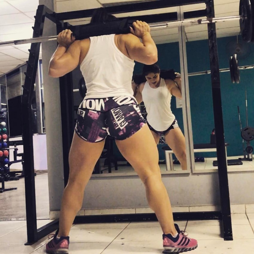 Flavia Baraky Tavares doing squats in the gym, while looking down at her feet