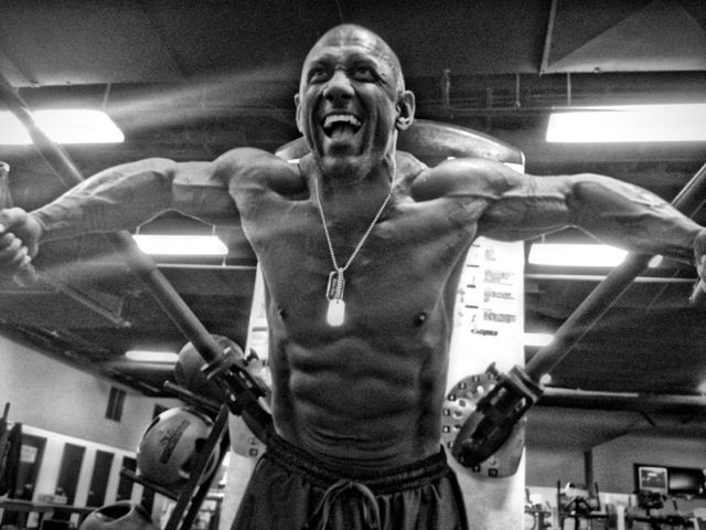 Jerry Ward doing chest cable flys in the gym, with a pained grimace on his face