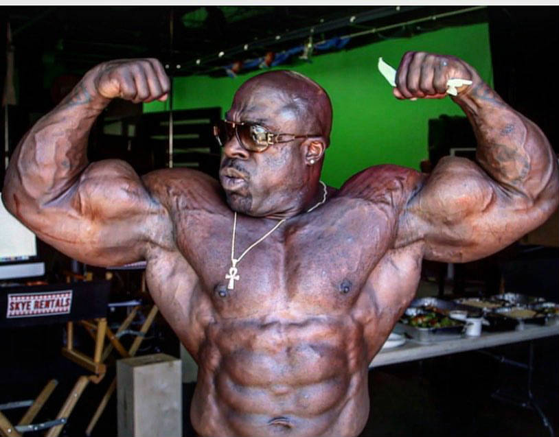 kali muscle tensing his arms with abs showing