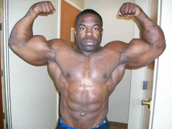 kali muscle tensing his biceps with arms over his head