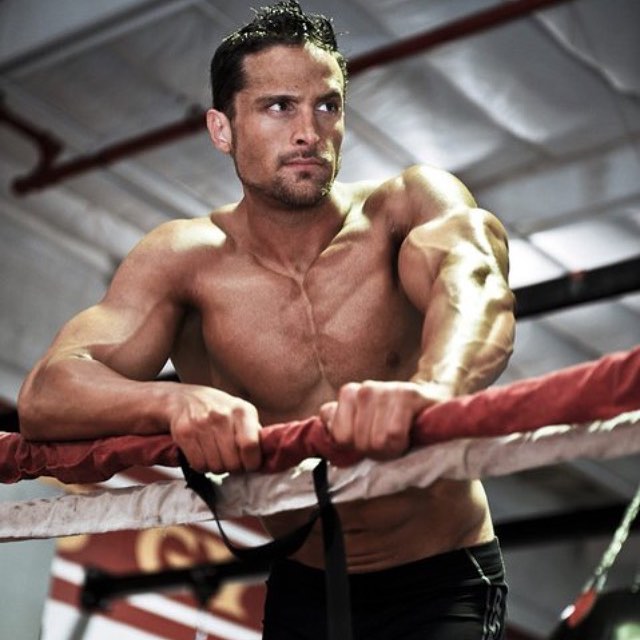 Layne Norton in a boxing ring looking in a distance while showing his sculpted chest and arms