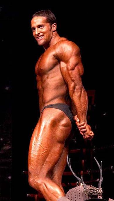 Layne Norton in a side triceps pose on a bodybuilding stage