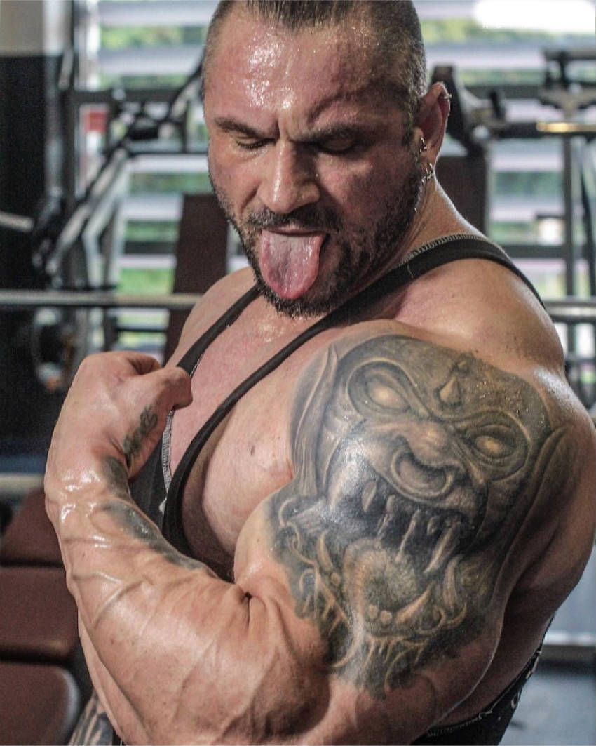 Miha Zupan tensing his bicep, showing a full upper arm tattoo of a devil