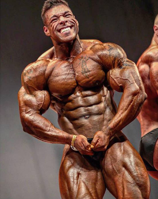 nathan de asha tensing his muscles at competition