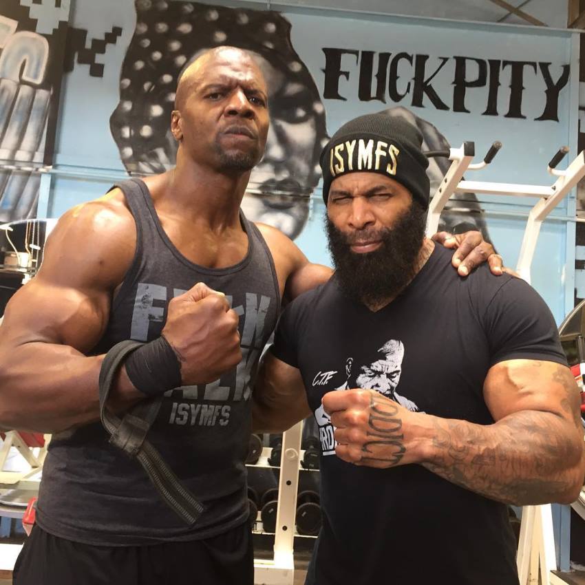 Terry Crews flexing his arm with CT Fletcher in a gym