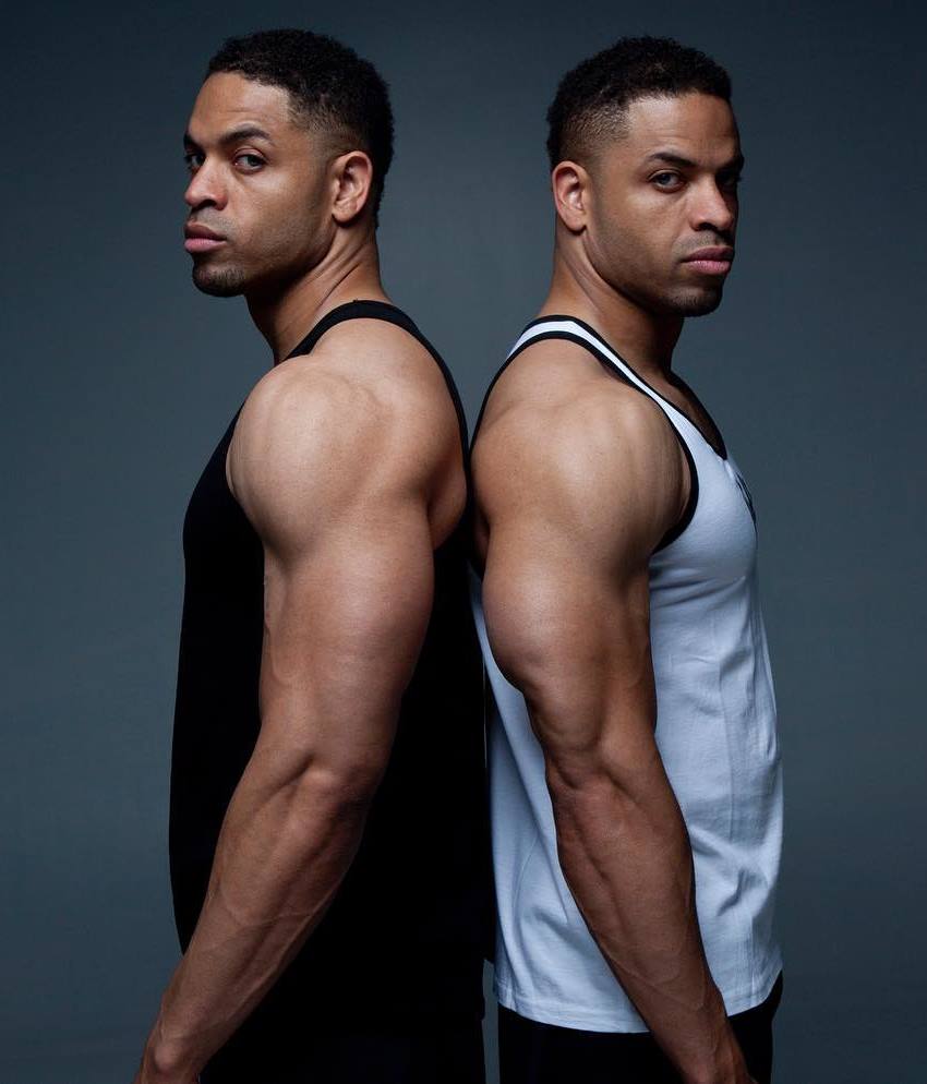 The Hodgetwins profile picture, where they have turned their backs to each other, and are looking directly into the camera
