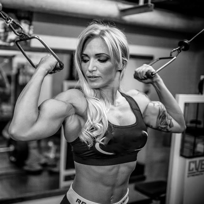 Black and white picture of Alina Pettke doing cable biceps curls while showing her lean abs